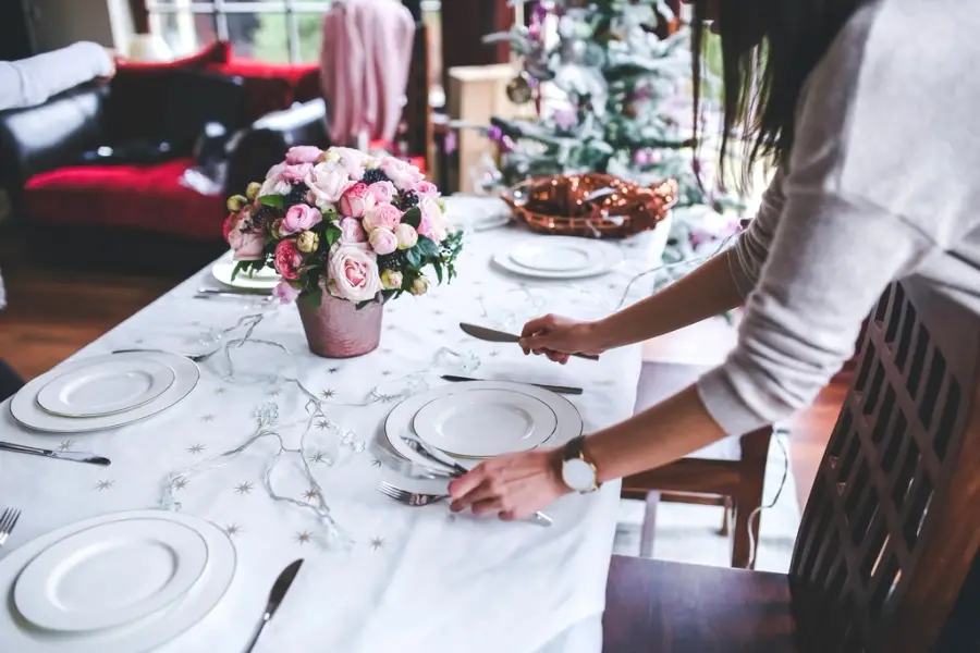 Reception table being set with plates and flowers