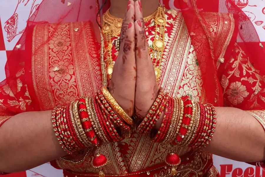 Bride in traditional red attire with folded hands